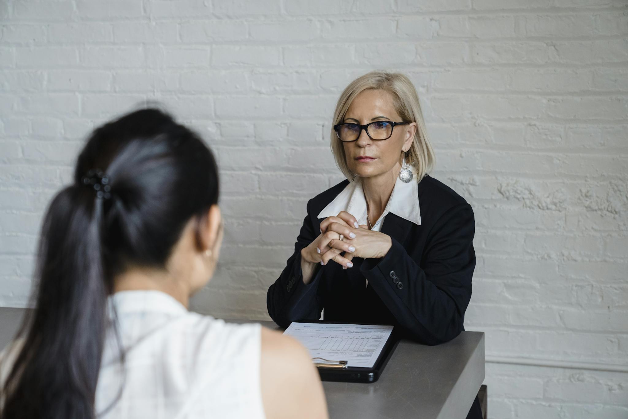 Professional businesswoman in a black blazer conducting an interview indoors.
